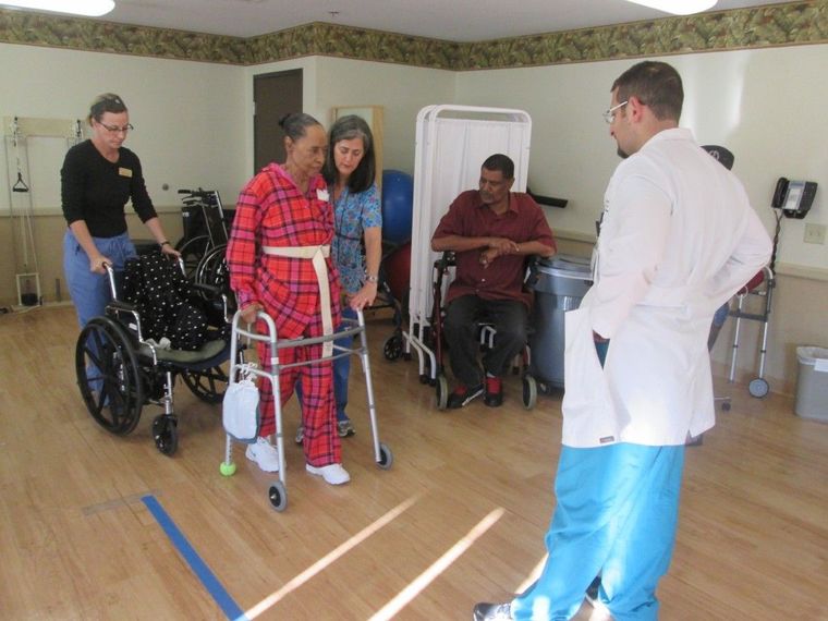 Nurses and doctor helping a woman to walk