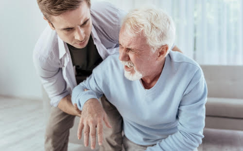 Man having a stroke while a younger man helps him